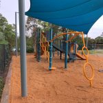 Tangerine coloured climbing piece on playground that spins with two circular sections on top of each other