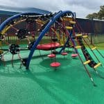 Arched climber with two bright blue arched beams linked with a black rubber belt and multiple climbers in red and yellow