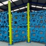 Three section climbing wall with turquoise honeycomb climbing panels and bright green posts