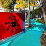 blue rubber wetpour sensory pathway through garden with sensory panels and flower shade