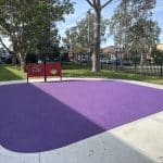 Bright purple rubber surfacing with a concrete pathway around