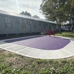 Bright purple rubber surfacing with a concrete pathway around