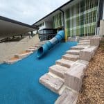 Blue tube embankment slide with blue rubber wetpour and sandstone logs tiered for steps