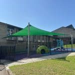 hypar sail shade structure over outdoor play area with galvanised posts and a green shade canopy