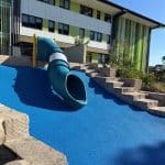 Blue Embankment Tunnel Slide with yellow support posts and sandstone blocks used for tiering with a blue rubber surface