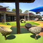 Vibrant early childhood playground with acorn-shaped sensory seats, crawling tunnel, and shaded climbing structure—designed to support safe, inclusive play and developmental learning in a well-equipped outdoor education setting.