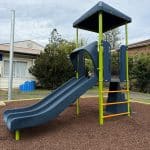 Play equipment with a single deck and a double navy blue slide, navy blue roof and multiple climbers including one with multiple orange rungs