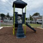 Play equipment with a single deck and a double navy blue slide, navy blue roof and multiple climbers including a navy blue plastic rotomoulded mountain style climber