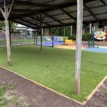 Green synthetic grass underneath a pitched roof timber shelter structure