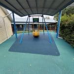 new rubber surfacing under an old swing with a turquoise coloured border and blue centre area