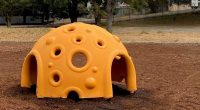 Plastic dome play item for children's playground with side entry points and a number of viewing holes for children to see through