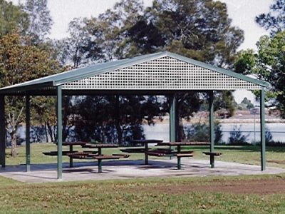 Large green gable roof shelter over picnic area with lattice infill panels at ends