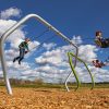 swing set with a modern twisted frame with kids swinging high up in to the sky